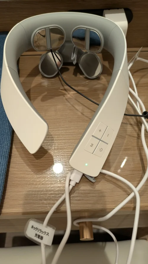 セルフケア個室に置かれた首用マッサージ機のネックリラックスと、専用の充電器