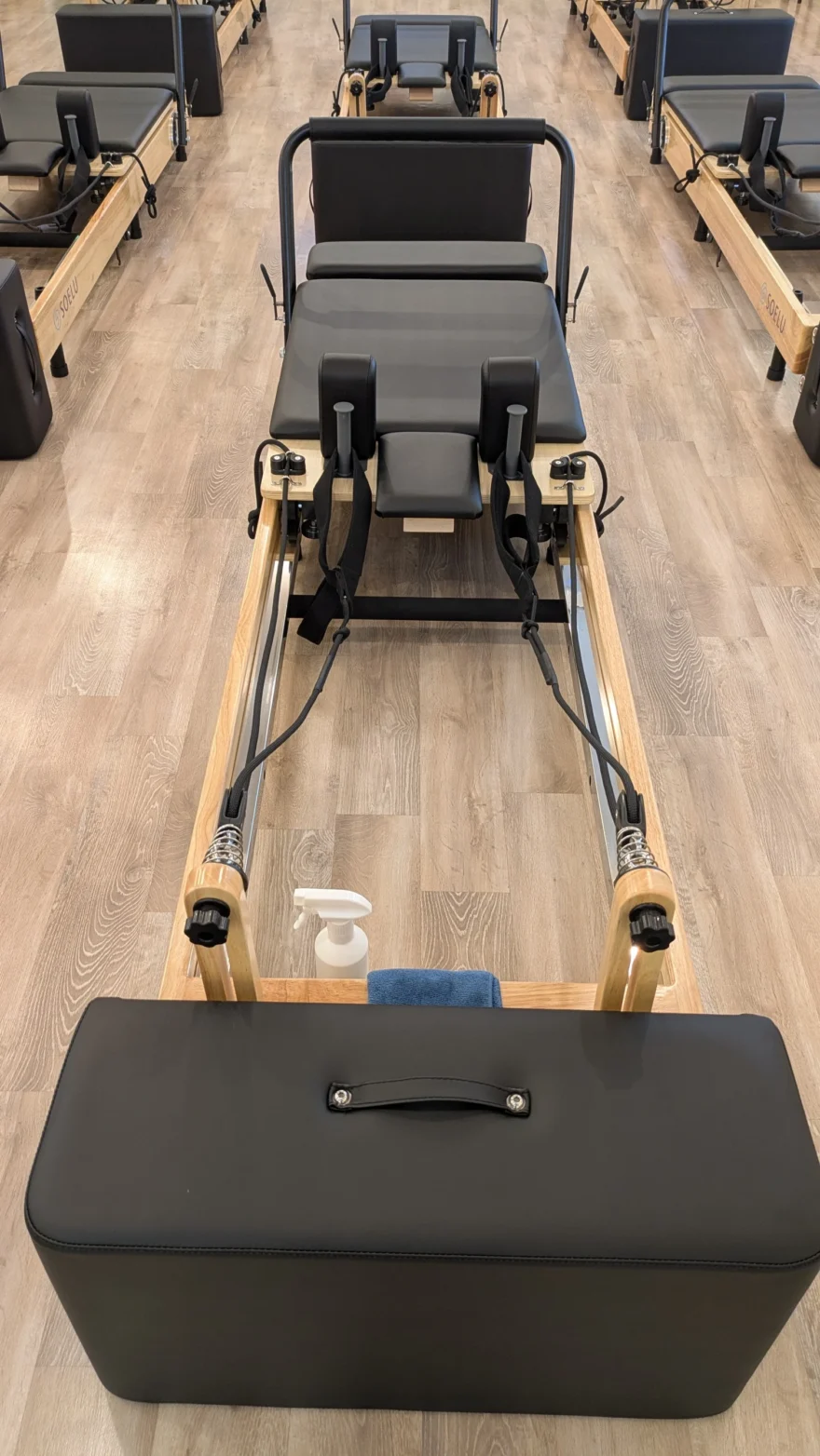 リフォーマーを正面から見たところ。ヘッドレストとストラップ、除菌スプレーとタオルが置かれている