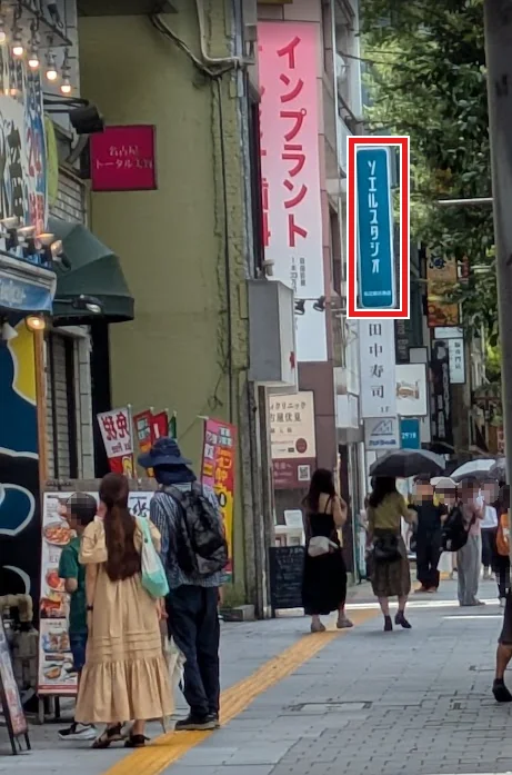 通りから見上げたソエルスタジオ名古屋伏見店の袖看板。周囲は飲食店やクリニックが並ぶ通り