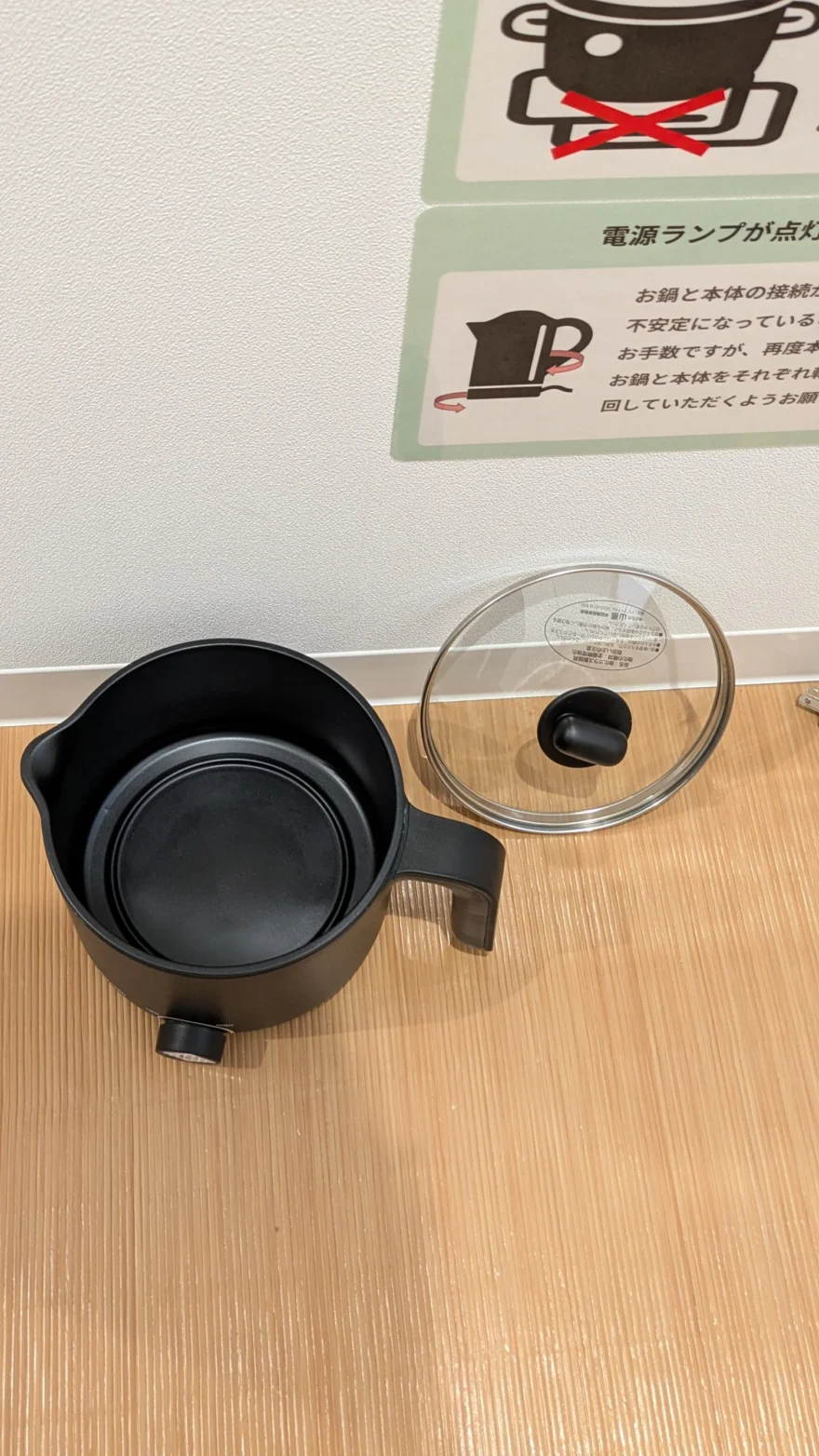 よもぎ蒸しで使う黒い鍋とガラス蓋。壁には鍋の扱い方の注意書きが貼られている