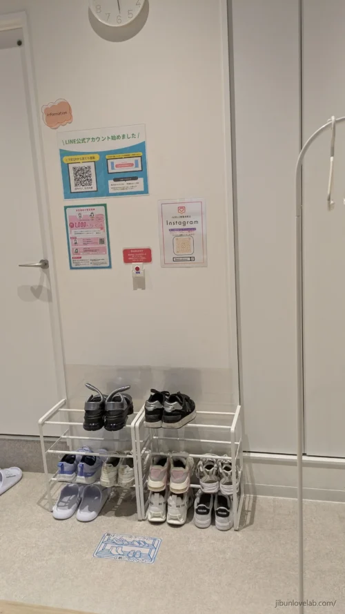 ソエルスタジオ堺筋本町店の入口内側にある靴箱。壁にLINE公式アカウントの案内と緊急ボタン